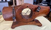 Front view of solid wood propeller with hollow center and attached metal fixtures, mounted on a wooden base.
