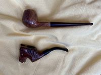 Two vintage smoking pipes: Medico classic pipe and carved horse head Bruyere pipe on fabric background