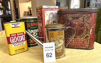Photo showing all 5 vintage tins with varying sizes and designs on a table.