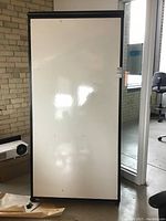 Front view of the large white board with black frame and reflective white surface.