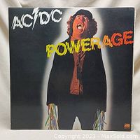 Front cover of AC/DC Powerage album showing band member with colorful wires and album title.