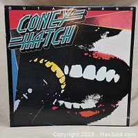 Front of album cover with bold graphic featuring band logo and abstract face design