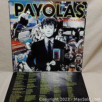 Front cover of Payola$ vinyl album with graphic collage and band member in a suit