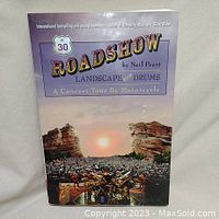 Front cover of 'Roadshow' book by Neil Peart showing a concert stage with drum kit and scenic landscape.