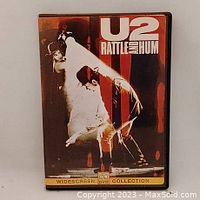 Front cover of U2 Rattle and Hum DVD showing graphic image of band members performing, title, and format information.