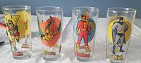 Photo showing all four glasses with full artwork of Robin, Aquaman, Shazam, and Batman side by side.