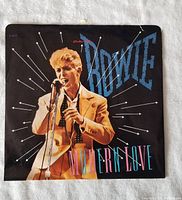 Front cover of David Bowie's 'Modern Love' 45 RPM vinyl single sleeve showing Bowie singing and stylized text.