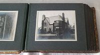 Open photo album page featuring a detailed black and white photograph of a stone house with a chimney and front porch.