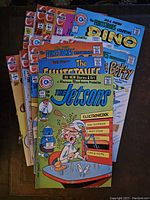 Photo showing 15 Charlton Comics from the 1970s arranged fanned out, featuring The Jetsons, The Flintstones, Betty, and others with colorful covers and vintage comic branding.