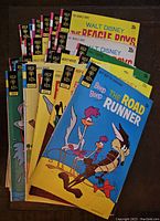 Photo of 25 Gold Key comic books from the 1970s laid out overlapping, showing covers featuring The Beagle Boys, Bugs Bunny, Mickey Mouse, Road Runner, and others. Colorful illustrated covers with vintage pricing and titles.