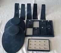 Various black velvet jewelry display stands including necklace busts, ring trays, and earring trays on a plain background.