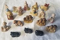 Front and top view of all 17 ceramic tea figurines including animal groups and human figures on a light background