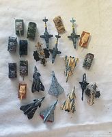 Top-down photo showing 22 miniature diecast military vehicles including tanks, jets, and helicopters arranged on a white background.