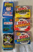 Image showing unopened baseball card packs including 1988 Leaf box, Eight Men Out pack, and several 1989 Topps Big Series packs.