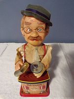 Front view of the vintage Charlie Weaver bartender toy, showing detailed facial features, glasses, hat and the coctail shaker and glass in hands.