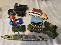Lot arranged on beige background showing all nine vintage toy vehicles including military tanks, troop truck with soldiers, civilian cars, and battleship.