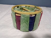 Side view of green marbled plastic carousel holder containing multiple stacks of Jello car coins in various colored edges including purple, blue, and red.