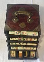 View of open top showing Mahjong tiles in five drawers inside the wooden case with brass handle and accents.
