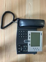 Top view of the Cisco 7961 IP phone showing the handset, numeric keypad, navigation and function buttons, and the LCD display screen.