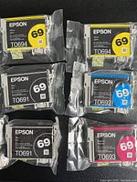 Six Epson 69 ink cartridges in original packaging, colors visible and labeled.