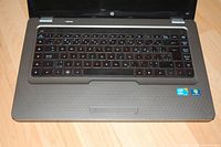 Top view of the HP laptop keyboard and palm rest showing the keyboard layout, touchpad, Intel Core i3 and Windows 7 stickers.