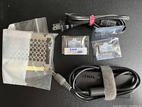 Photo showing Lenovo charger with attached power cable, two hard drive trays in protective packaging, and two Wireless-N 2200 MiniPCI wireless cards in plastic bags.