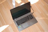 Open laptop showing keyboard, trackpad, screen off, power cable attached