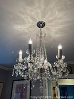 Front view of chandelier installed and illuminated showing six arms with crystal bead strands