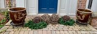 Two brown glazed Chinese ceramic planters with dragon relief on black metal stands, flanking five grapevine balls and artificial fir wreaths