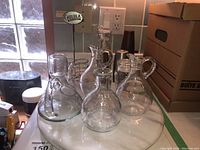 Four glass cruets on white marble lazy Susan on countertop with cardboard boxes in background