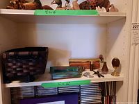 Shelf display showing various kaleidoscopes, a dark woven basket on a stand, several kaleidoscopes with stained glass and marbles, and a wood egg on brass stand.