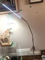 Full view of the standing LED floor lamp lit, showing the flexible arm and chrome finish.