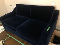Front view of navy blue velvet loveseat showing two seat and back cushions on hardwood floor