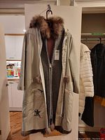 Full view of beige outer parka with fur-edged hood and inner liner