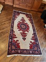 Overall top view of entire rug laid on hardwood floor showing field, border and fringe