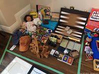 Wide shot showing entire lot including dolls, backgammon set, cards, puzzles, and other toys