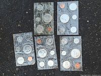 Five sealed original Royal Canadian Mint uncirculated coin sets displayed on asphalt