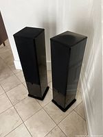 Pair of tower speakers standing side by side with grills on