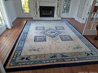 Full view of ivory field rug laid on hardwood floor in front of marble fireplace