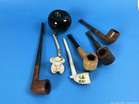 Group photo of 6 vintage pipes on blue background, including a green apple for size reference.