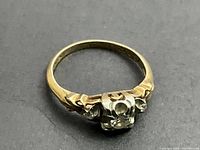 Yellow gold and white gold prong setting, top view of central diamond and side stones on gray background
