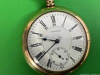 Close-up of white enamel dial showing Roman numerals, subsidiary seconds, and blued steel hands