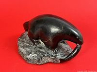 Front view of black soapstone seal holding a fish, showing size and detail.