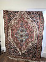 Full view of rug hung vertically showing overall medallion design and border