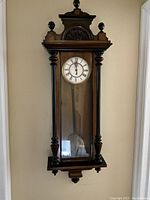 Front view of glazed mahogany Vienna wall clock case with turned finial pediments and mounts