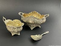 Group view of sugar dish, creamer and caddy spoon on black background