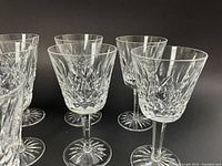 Front view showing all eight crystal wine glasses against a black background.