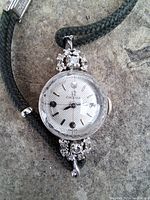 Front view of the watch showing dial, diamond clusters and green braided silk band