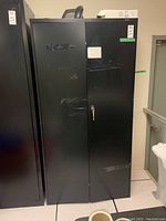 Full frontal view of the black metal storage cabinet showing two doors and lock.