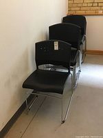 Front view showing the black molded plastic seat and backrest with ventilation holes, and chrome sled legs.